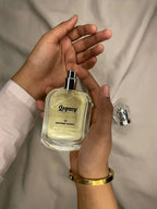 Hand holding a 'Legacy' perfume bottle with a plain background