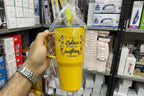 Yellow mug with motivational quote held in a hand against a store shelf background